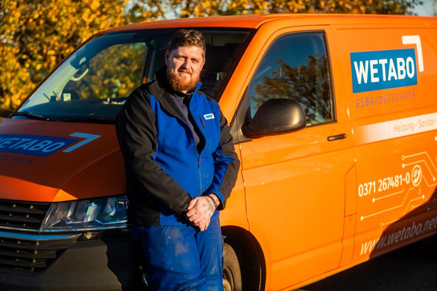 WETABO-Monteur vor dem orangen Firmentransporter
