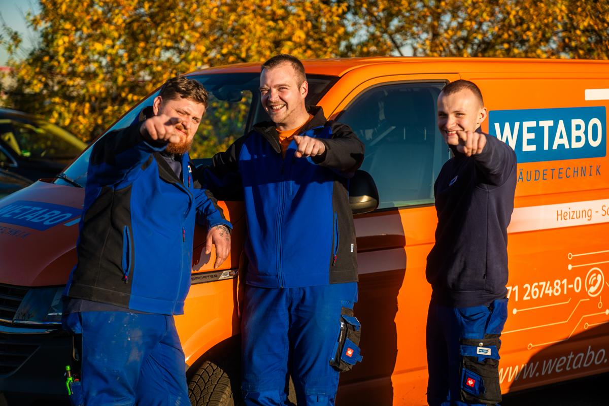 Drei WETABO-Monteure vor dem orangen Firmentransporter